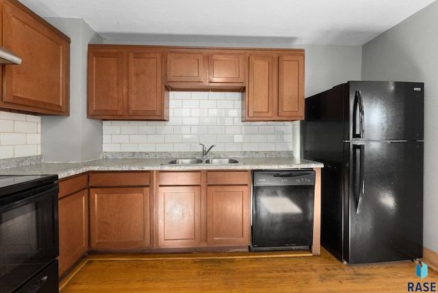 kitchen featuring light hardwood / wood-style floors, sink, black appliances, and tasteful backsplash