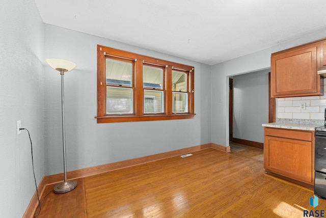 kitchen with decorative backsplash, electric range oven, and light hardwood / wood-style floors