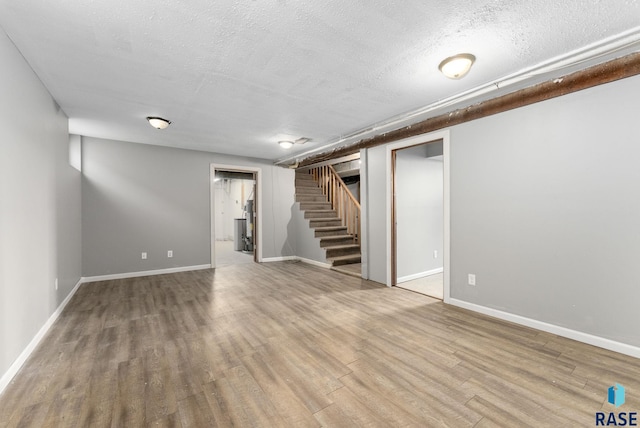 basement featuring light wood-type flooring and a textured ceiling