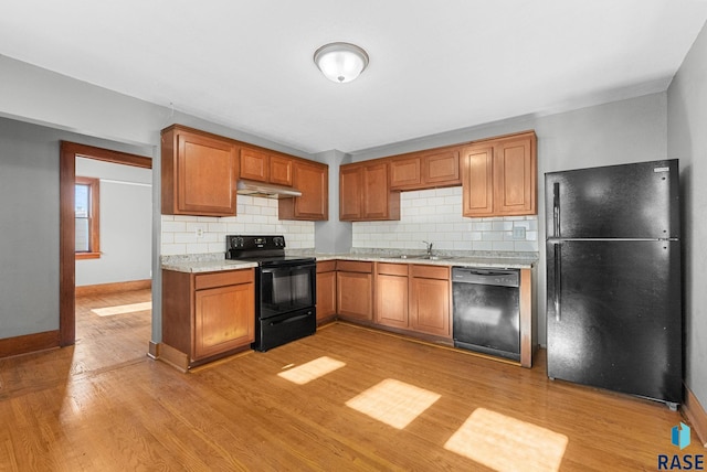 kitchen featuring sink, decorative backsplash, light hardwood / wood-style flooring, and black appliances