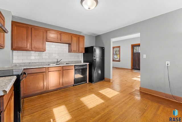 kitchen featuring black appliances, sink, tasteful backsplash, and light hardwood / wood-style floors