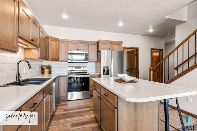 kitchen with a center island, appliances with stainless steel finishes, decorative backsplash, sink, and dark hardwood / wood-style floors