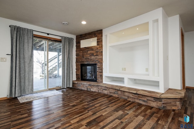 unfurnished living room featuring built in features, wood finished floors, and a stone fireplace