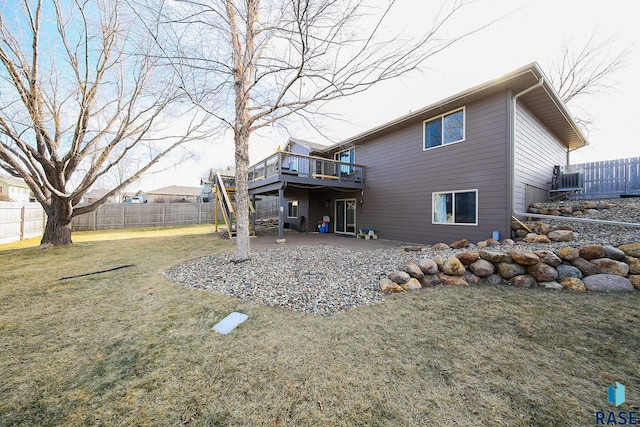 back of house featuring a lawn, a deck, and a patio