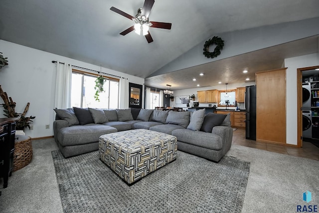 living room featuring a healthy amount of sunlight, stacked washer / dryer, carpet floors, and lofted ceiling