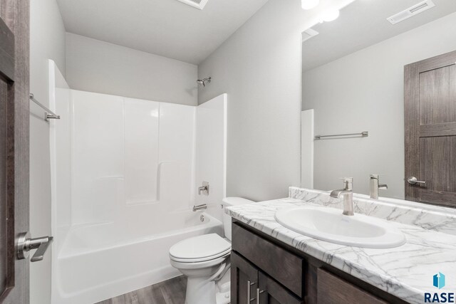 full bathroom with hardwood / wood-style floors, toilet, shower / tub combination, and vanity