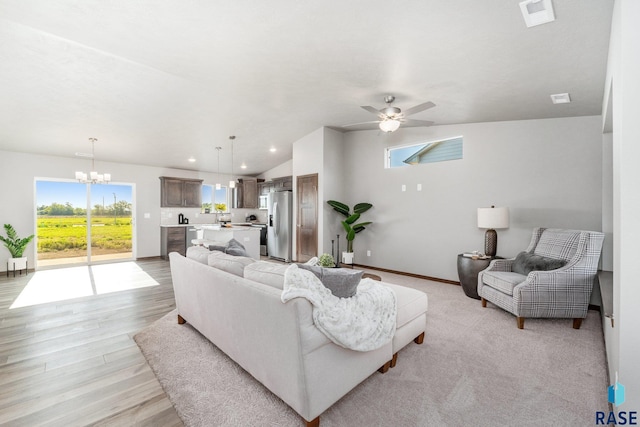 living room featuring light wood-type flooring, ceiling fan with notable chandelier, and lofted ceiling