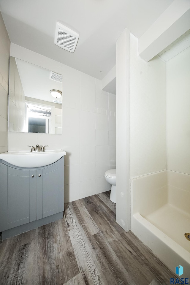 bathroom with wood-type flooring, toilet, walk in shower, and vanity