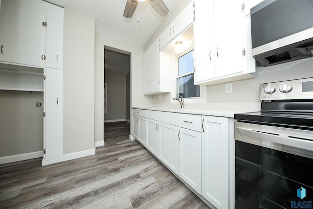 kitchen with ceiling fan, light hardwood / wood-style floors, white cabinets, sink, and stainless steel appliances