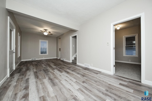 empty room featuring ceiling fan, a textured ceiling, and light hardwood / wood-style flooring