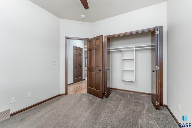 unfurnished bedroom with ceiling fan, dark carpet, and a closet