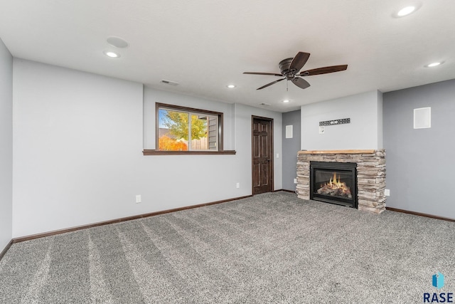 unfurnished living room featuring ceiling fan, a stone fireplace, and carpet flooring