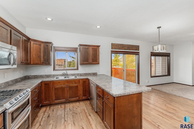 kitchen with kitchen peninsula, light hardwood / wood-style flooring, sink, decorative light fixtures, and stainless steel appliances