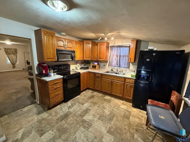 kitchen featuring sink, black appliances, a textured ceiling, and vaulted ceiling