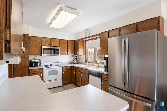 kitchen featuring sink, light hardwood / wood-style flooring, appliances with stainless steel finishes, and a textured ceiling