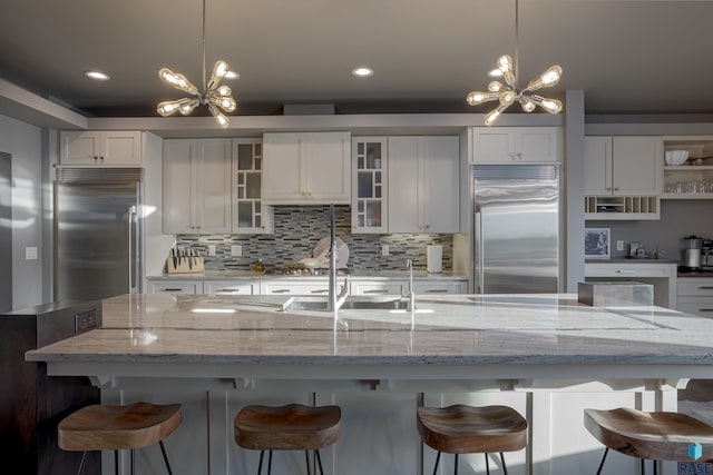 kitchen with decorative light fixtures, a large island, and stainless steel built in refrigerator