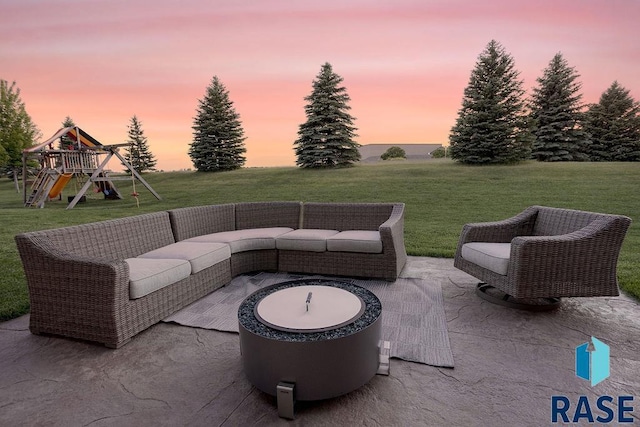 patio terrace at dusk featuring a lawn, an outdoor living space with a fire pit, and a playground