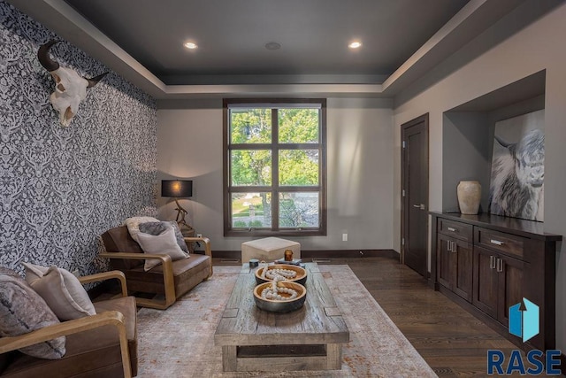 living area with a tray ceiling and dark hardwood / wood-style floors