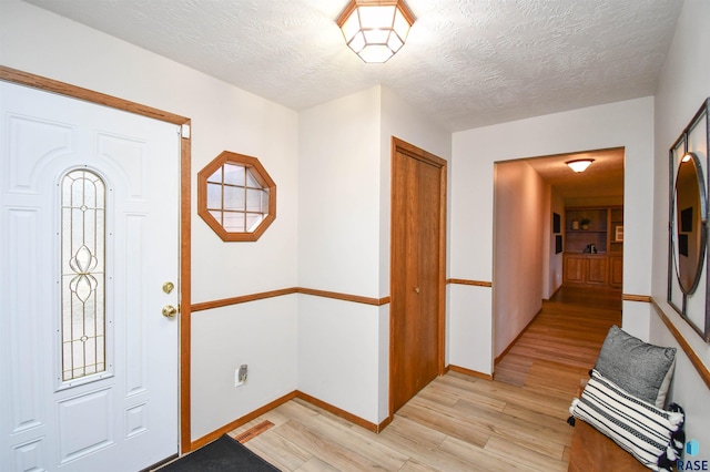 foyer with a textured ceiling and light hardwood / wood-style flooring