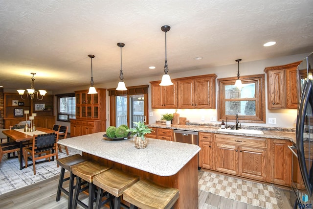 kitchen featuring sink, hanging light fixtures, a center island, and light hardwood / wood-style flooring