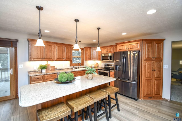 kitchen featuring a center island, hanging light fixtures, a kitchen breakfast bar, sink, and stainless steel appliances