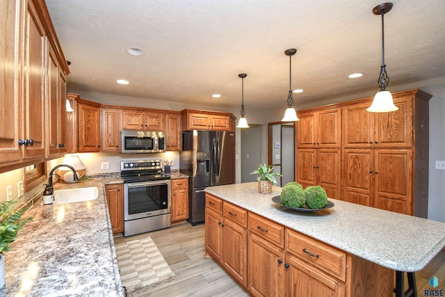 kitchen with a kitchen island, sink, hanging light fixtures, and stainless steel appliances