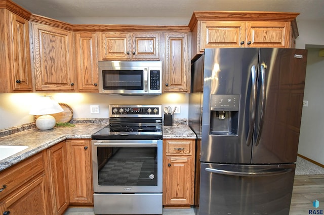 kitchen with light stone counters, light hardwood / wood-style flooring, and appliances with stainless steel finishes