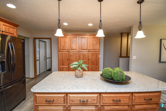 kitchen featuring a kitchen island, light hardwood / wood-style floors, pendant lighting, and refrigerator with ice dispenser