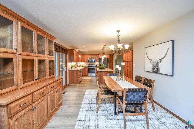 dining area with sink, an inviting chandelier, and light hardwood / wood-style flooring