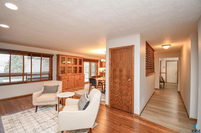 sitting room featuring a textured ceiling, light hardwood / wood-style flooring, and a notable chandelier