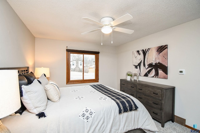 carpeted bedroom featuring ceiling fan and a textured ceiling