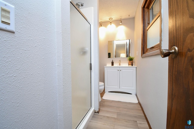 bathroom with vanity, toilet, hardwood / wood-style floors, and a shower with door