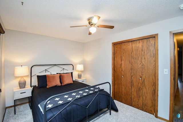 carpeted bedroom with a textured ceiling, a closet, and ceiling fan