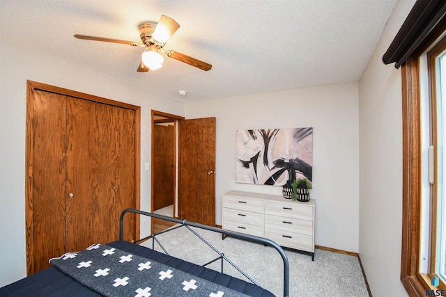 bedroom with light carpet, a textured ceiling, a closet, and ceiling fan