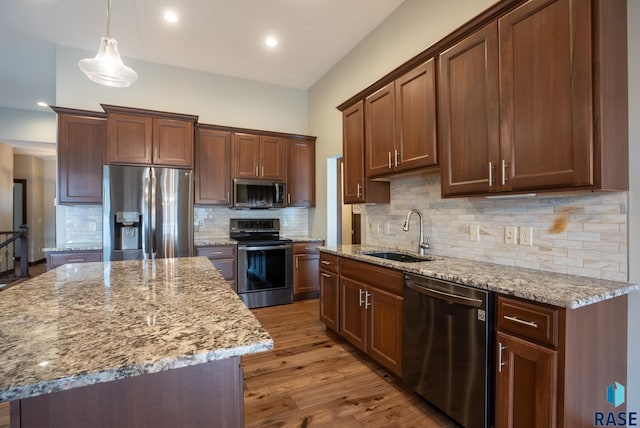 kitchen with sink, stainless steel appliances, a kitchen island, and hanging light fixtures