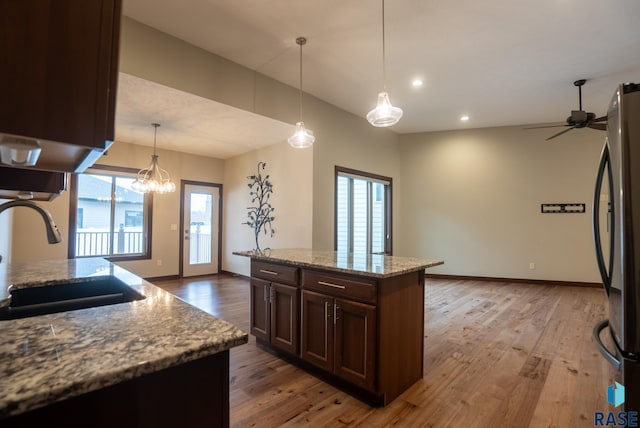 kitchen featuring a kitchen island, sink, refrigerator, and light stone counters