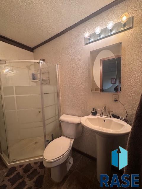 bathroom featuring tile patterned floors, toilet, a textured ceiling, walk in shower, and ornamental molding