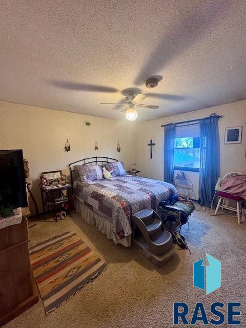 carpeted bedroom with ceiling fan and a textured ceiling