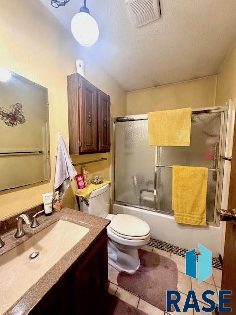 full bathroom with vanity, toilet, combined bath / shower with glass door, and tile patterned floors