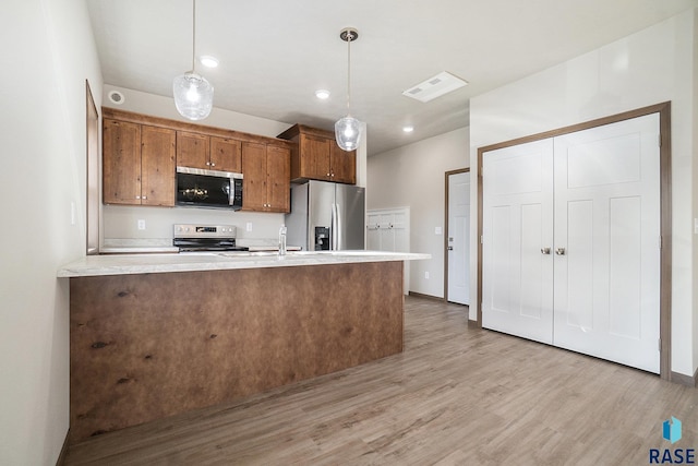 kitchen featuring hanging light fixtures, appliances with stainless steel finishes, and light hardwood / wood-style flooring