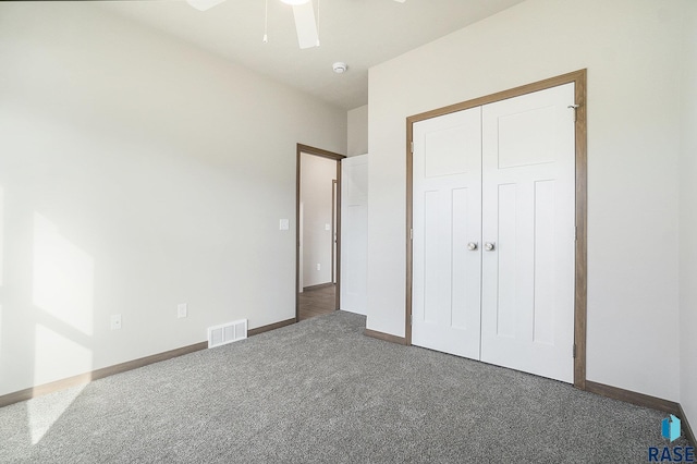 unfurnished bedroom featuring dark carpet, ceiling fan, and a closet