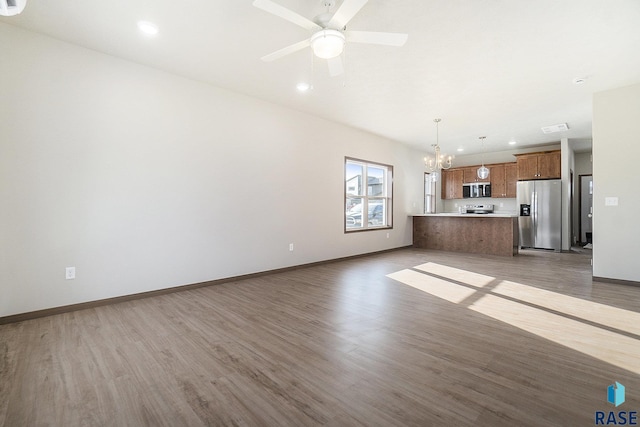 unfurnished living room featuring hardwood / wood-style flooring and ceiling fan with notable chandelier