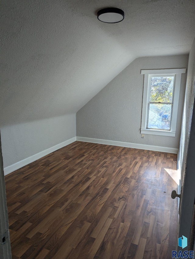 bonus room with dark wood-type flooring, a textured ceiling, and lofted ceiling