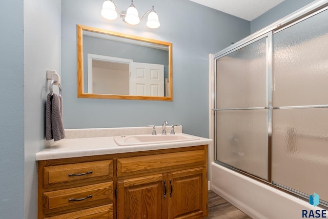 bathroom with bath / shower combo with glass door, vanity, and hardwood / wood-style floors