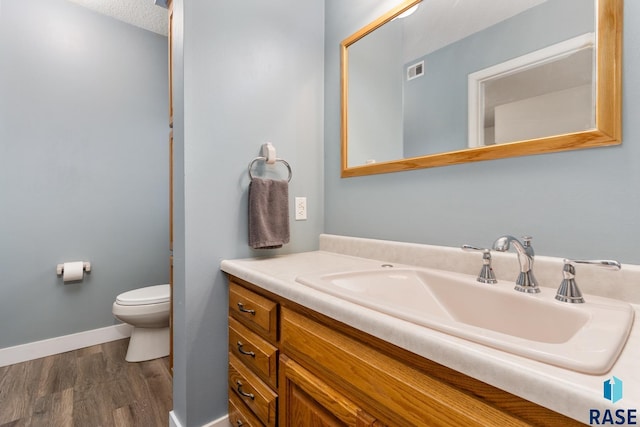 bathroom with hardwood / wood-style flooring, a textured ceiling, toilet, and vanity