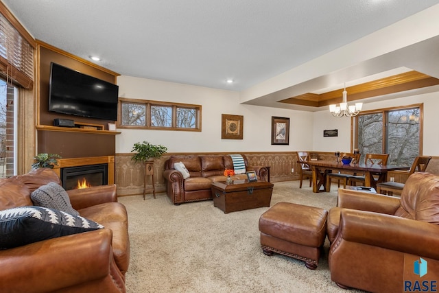 carpeted living room with a notable chandelier and a tray ceiling