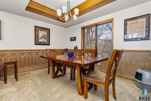 dining room with carpet, a raised ceiling, and an inviting chandelier