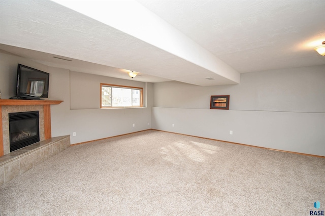 unfurnished living room featuring a tiled fireplace, a textured ceiling, and carpet