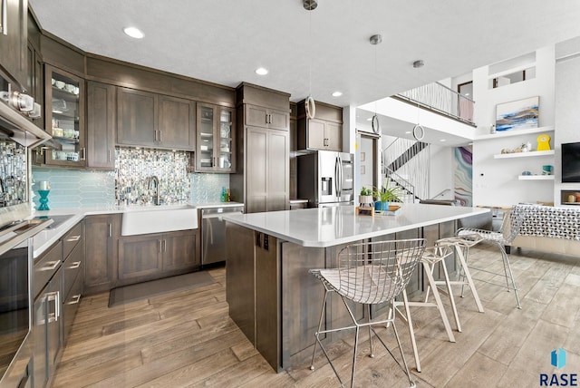 kitchen with appliances with stainless steel finishes, a center island, sink, a kitchen breakfast bar, and hanging light fixtures