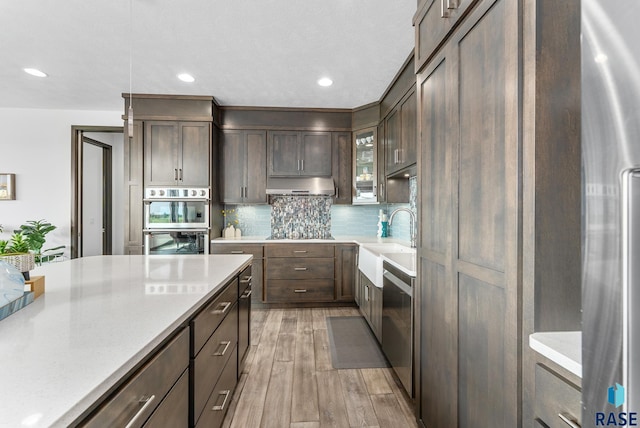 kitchen with sink, stainless steel appliances, dark brown cabinetry, and light hardwood / wood-style floors